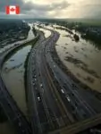 Наводнение в долине Фрейзер, Канада: люди эвакуируются из затопленных домов, хаос на дорогах с обломками и водой, драматическое небо после ливня, напряжённая атмосфера, широкий аэриальный кадр в реалистичном стиле.
