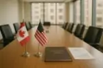 Стол переговоров с настольными флагами Канады и США и папкой о суверенитете в светлом зале