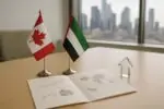 Флаги Канады и ОАЭ на столе рядом с папкой с нейтральными графиками инвестиций и торговли, дневной свет.