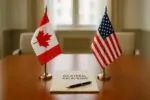 Флаги Канады и США на столе в переговорной, между ними зазор и папка «Bilateral Relations»