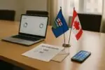 Стол в современном офисе: ноутбук с нейтральной аналитикой, бланк голосования и флаги Альберты и Канады.