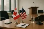 Флаги Канады и США рядом на столе в светлом зале, блокнот и телефон как символ осторожных переговоров
