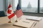 Флаги Канады и США рядом с папкой «CUSMA» и документами на столе в светлой переговорной