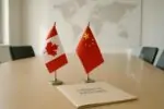 Флаги Канады и Китая на столе переговоров рядом с папкой «Finance Briefing» в светлом офисе