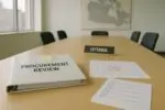 Светлый офис в Оттаве: папка “Procurement Review”, чек-лист и календарь с зачёркнутым сроком на столе