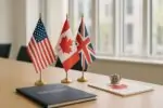 Светлый переговорный стол с флагами США, Канады и Британии и символом короны рядом с кленовым листом
