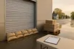 Склад малого бизнеса в Онтарио после наводнения: мешки с песком у ворот, влажные коробки и след воды.