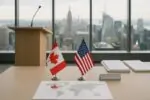 Стол с флажками Канады и США, документы и карта с торговыми маршрутами на фоне окон Нью-Йорка