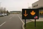 Пустые полосы у погранперехода Канада—США и табло со стрелкой вниз как символ снижения поездок