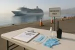 Портовая зона на Канарах: на столе средства санитарной безопасности, на фоне стоит круизный лайнер
