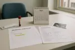 Стол в клинике: чек-лист дородового скрининга и календарь с отмеченными сроками, символ задержки теста