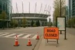 Тихая улица у стадиона BC Place в Ванкувере с табличкой о перекрытии и конусами, ясный день