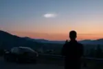 Спокойный вечерний пейзаж Британской Колумбии: у горизонта в небе виден размытый белый светлый объект.