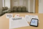 Светлый зал госуслуг в Канаде: на стойке бланк Employment Insurance и разрозненные табели смен, символ недоступности выплат