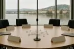 Пустой круглый стол саммита и символ сети из колец в центре, мягкий дневной свет, нейтральная атмосфера
