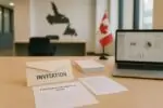 Стол в современном офисе с письмом «Invitation», формой EOI и картой Ньюфаундленда на фоне