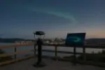 Смотровая площадка в Канаде: городские огни вдали и лёгкая зелёная полоса авроры на вечернем небе