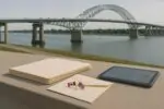 Папка с документами и планшет на фоне современного пограничного моста Канада—США, ясный день