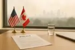 Офисный стол с флагами США и Канады и документом, за окном лёгкая дымка от пожаров над городом