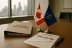Папка о закупках обороны, лист бюджета на $800 млн и небольшие флажки Канады и альянса на столе