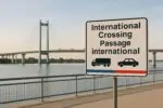 Современный вантовый мост через реку и нейтральный знак «международный переход», символ торговли Канады и США