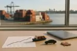 График ВВП на столе у окна и размытый порт с контейнерами на фоне, символ роста экспорта Канады