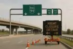 Дневной вид развязки с указателями Hwy 99 и электронным табло о ночном перекрытии и объезде.