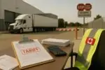 Спокойный грузовой терминал у границы: документы с отметкой «тарифы» и грузовик на заднем плане