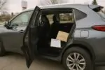 Открытая задняя дверь кроссовера, на втором ряду лежит уведомление об отзыве и лист сервиса