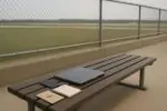 Скамья у ограждения рядом с аэропортом: закрытый ноутбук, телефон и блокнот, спокойный дневной свет